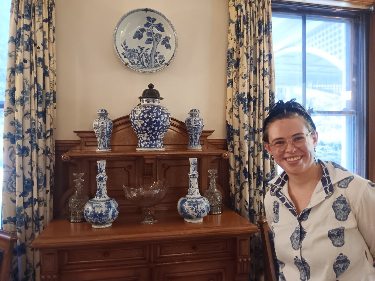 Lex with Ceramics curator posing with ceramics in the Marsh-Billings-Rockefeller mansion wearing a blue and white shirt that matches the ceramics