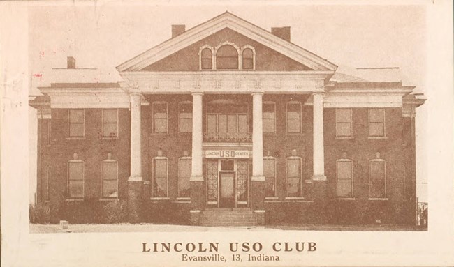 Lincoln USO Club Sepia-toned photograph of a symmetrical brick building fronted with four white columns and a portico. A “Lincoln USO Center” banner is hung above the door between the columns. The front of the building has two rows of windows.