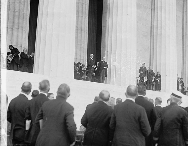 Photo of Lincoln Memorial dedication looking up at men standing in the memorial, crowds gathered in foreground