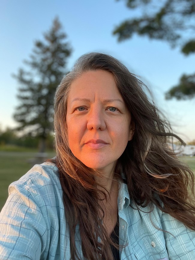 Dr. Lisa Fink An individual with long brown hair wearing a blue shirt.