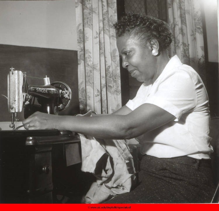 A Black woman sews with a singer sewing machine.