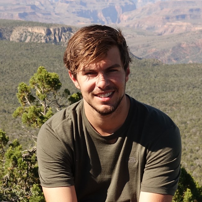 Logan Combs Closeup of man sitting outdoors smiling at camera