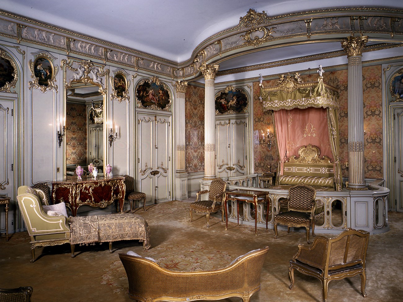 A large bedroom with silk upholstered and paneled walls.