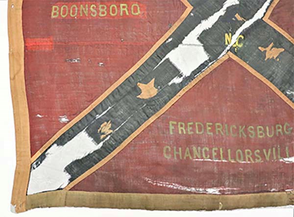 Lower left corner of 2nd N.C. flag The bottom left corner of a battle flag with red fabric outlined in white fabric and intersected by a blue fabric X with stars on it, the words "Boonsboro, Fredericksburg and Chancellorsville" are seen.