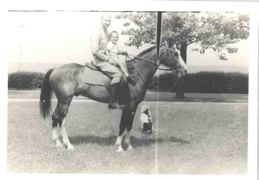 a man sits on a horse with his son in front of him