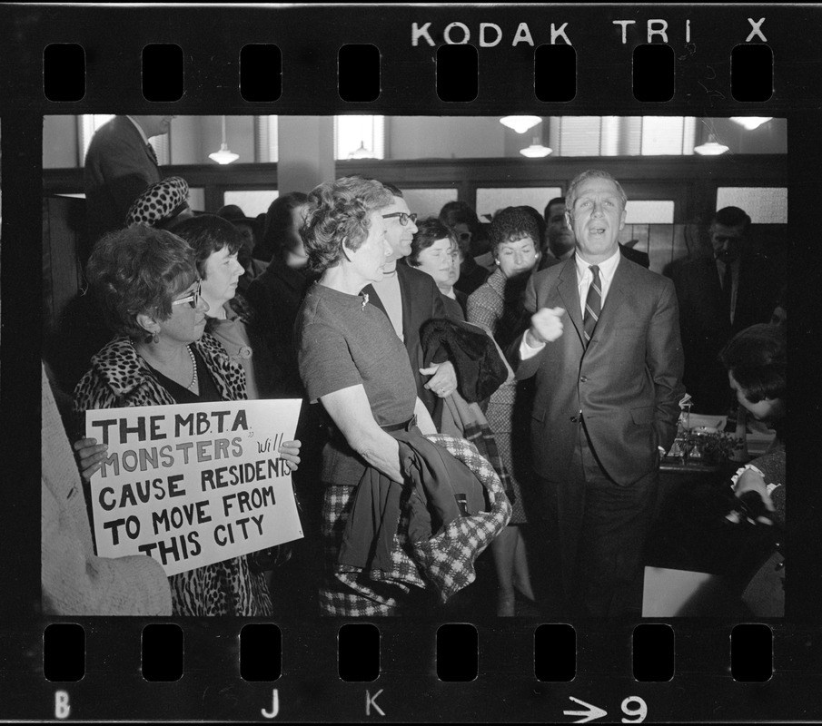 A man talking to people holding signs