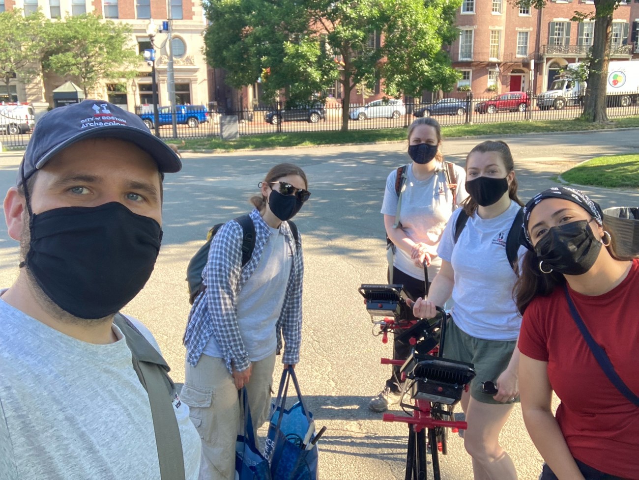 A group of five people in masks standing in the Boston Commons