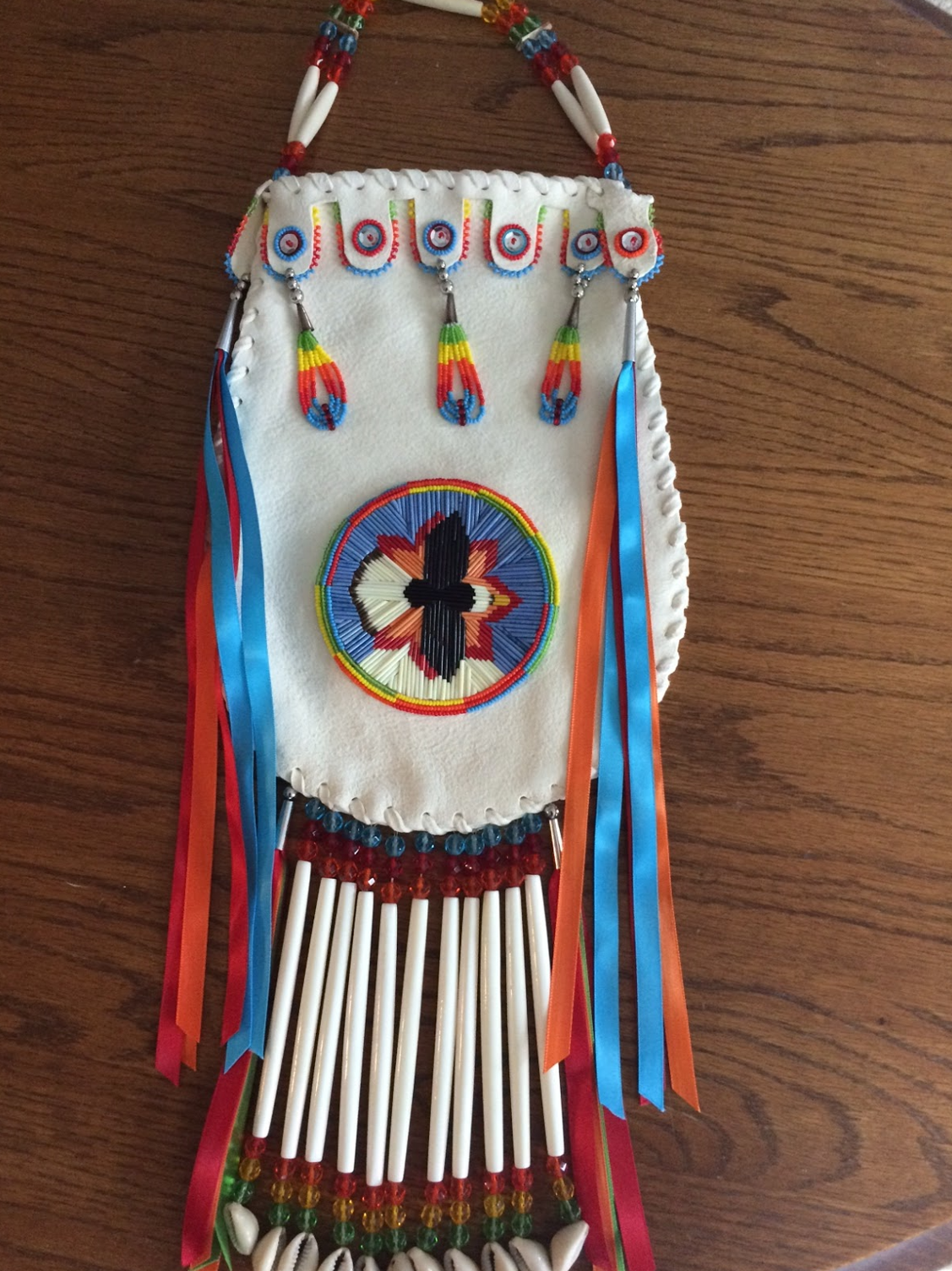 A purse made of white leather decorated in indigenous style with an eagle centerpiece.