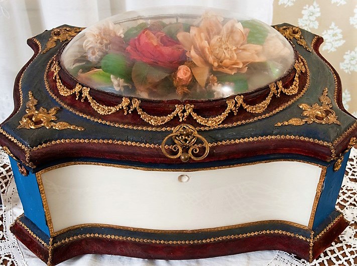 Porcelain box topped with colorful flowers encased in glass