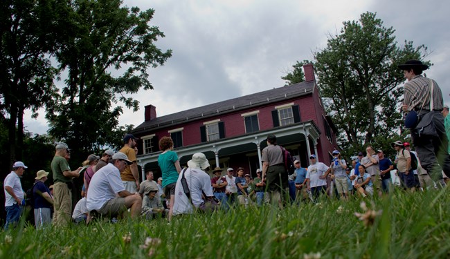 A park ranger speaks to a group of visitors in front of the Worthington House.