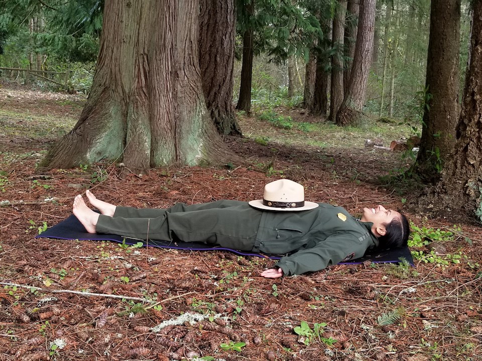 Mount Rainier Yoga: Feel the Earth Pose A ranger lies flat on their back in a yoga pose.