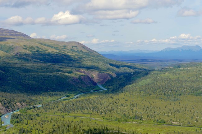 Image of a wide landscape and mountains with a river running through it.