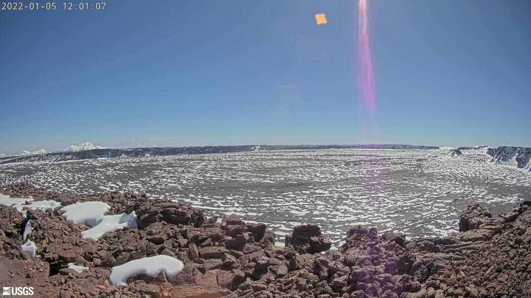 Photo of a barren summit crater with patches of snow