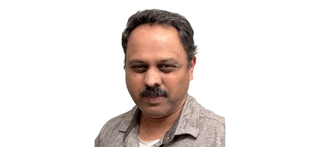 Headshot of man with dark hair and mustache in a light gray shirt