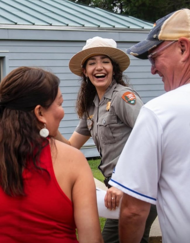 A park ranger smiles at a group of people