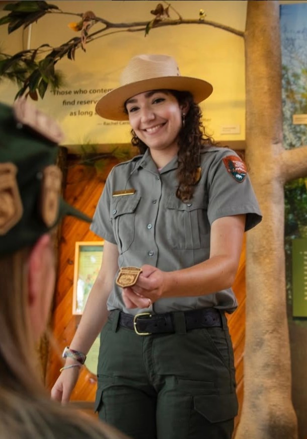 A park ranger hands out a junior ranger badge.