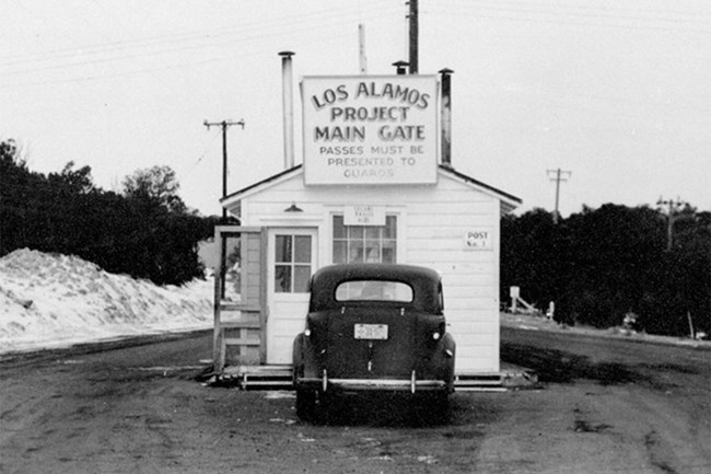 Black and white photo of a checkpoint with 1940s car at front.