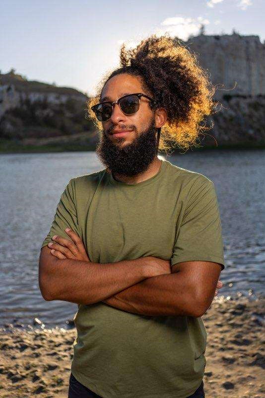 Malcolm a bearded black man wearing glasses and a bun in his hair