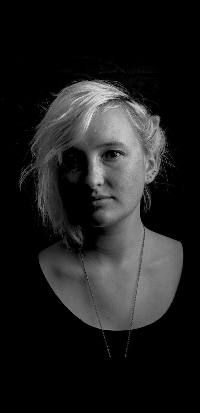 Portrait of a woman with light hair, earrings, and a necklace