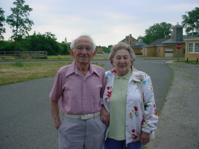 an elderly white couple pose in front of historic buildings