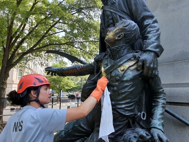 Mara removing graffiti off of one of the bronze figures on the Kościuszko monument located in Lafayette park Washington D.C.