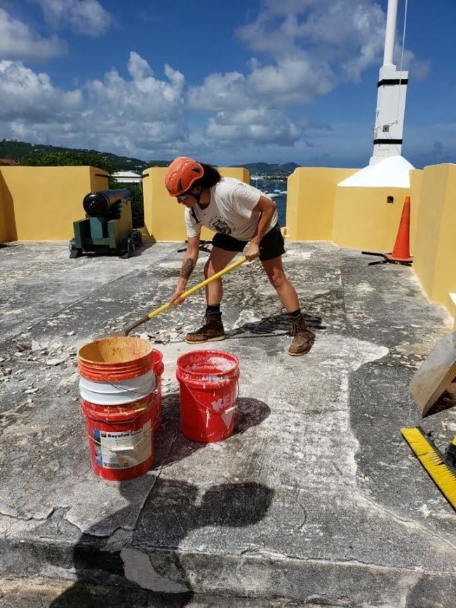 Mara working on Fort Christiansted in Saint Croix to remove deteriorating cement on the Northwest bastion using a roofers pitch fork in preparation to lay a new pad.