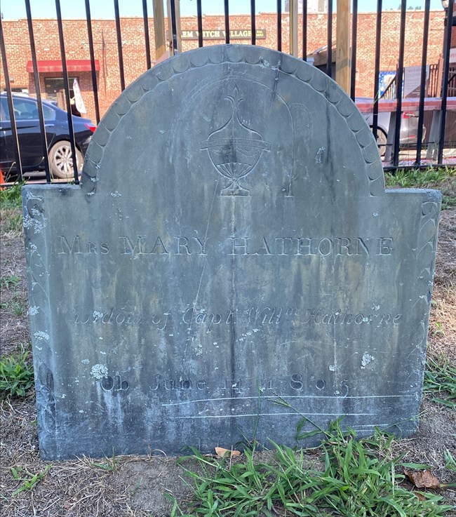 Gravestone of Mary Hathorne Gray gravestone with urn etched at top.