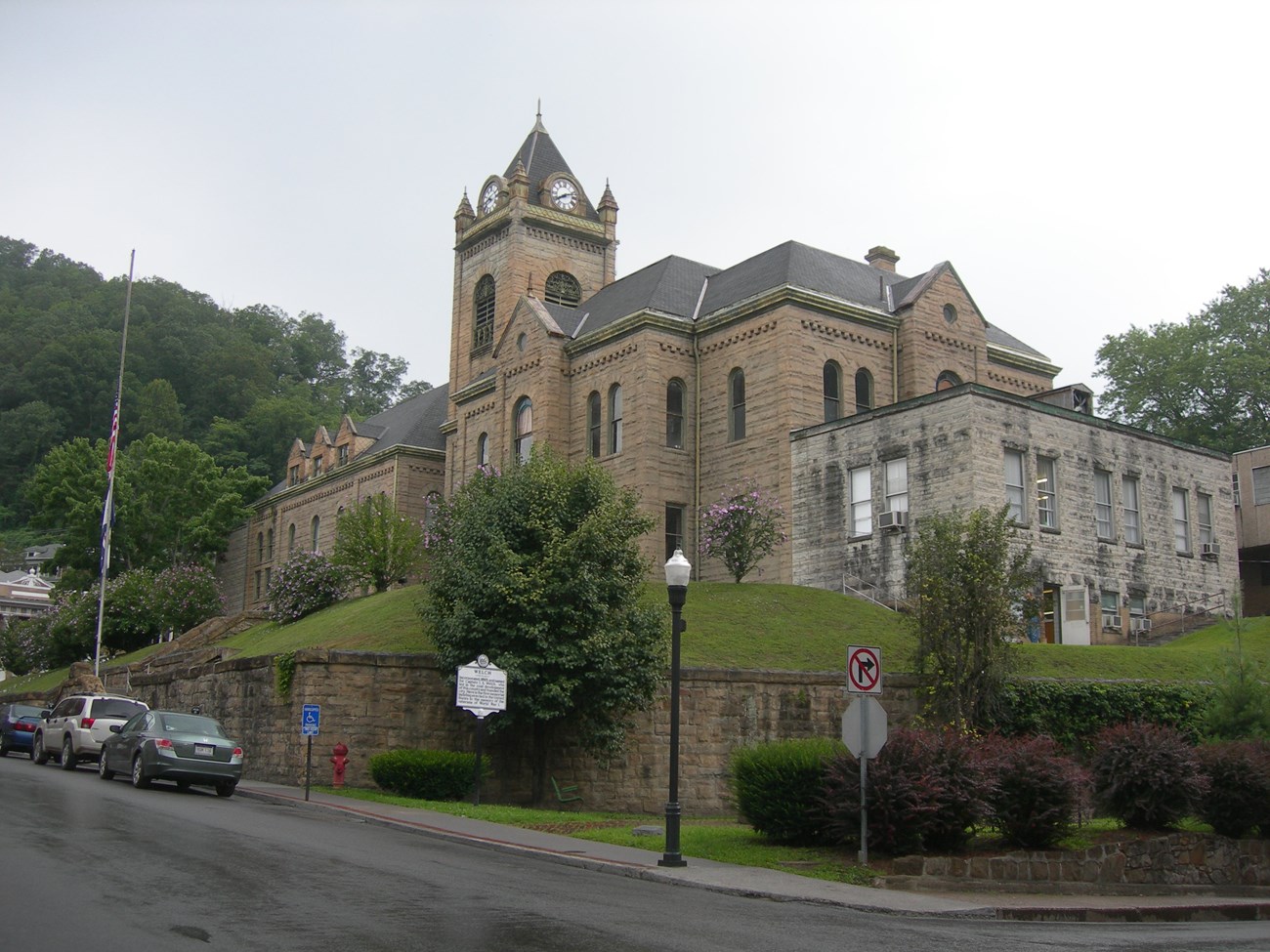 A large stone building sits atop a turf hill. The building is dominated by a large square tower rising from the structure's center.