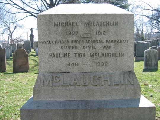 Light grey gravestone, with inscription, in a cemetery, surrounded by other gravestones
