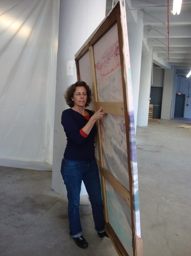 Susan Duhl moving a water damaged painting during recovery work after Hurricane Sandy.