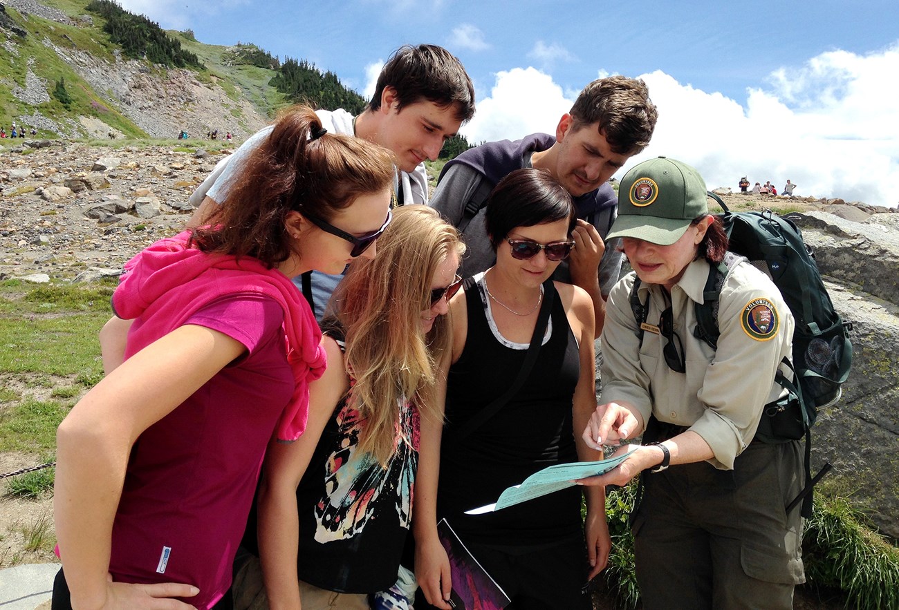 A few people gather around a map that a uniformed person is showing.