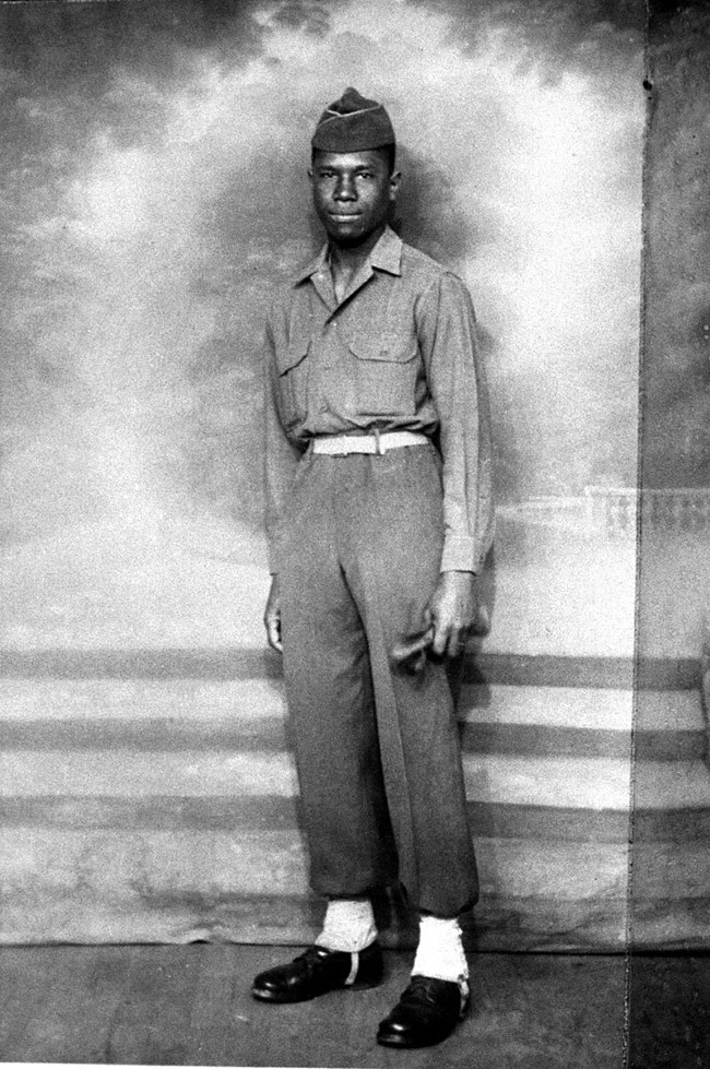 A black and white image of a man standing in a U.S. army uniform