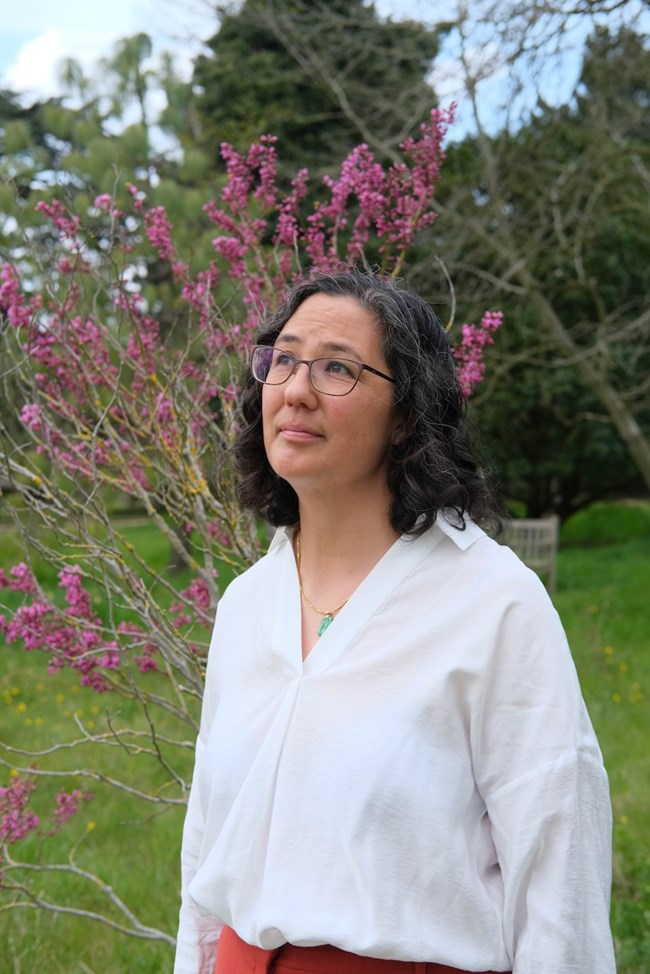 Melissa Fu, photo by Sophie Davidson A woman stands in front of a flowering tree, looking up at the sky.