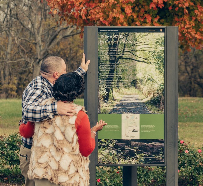 Middle aged couple standing reading a vertical wayside at a park