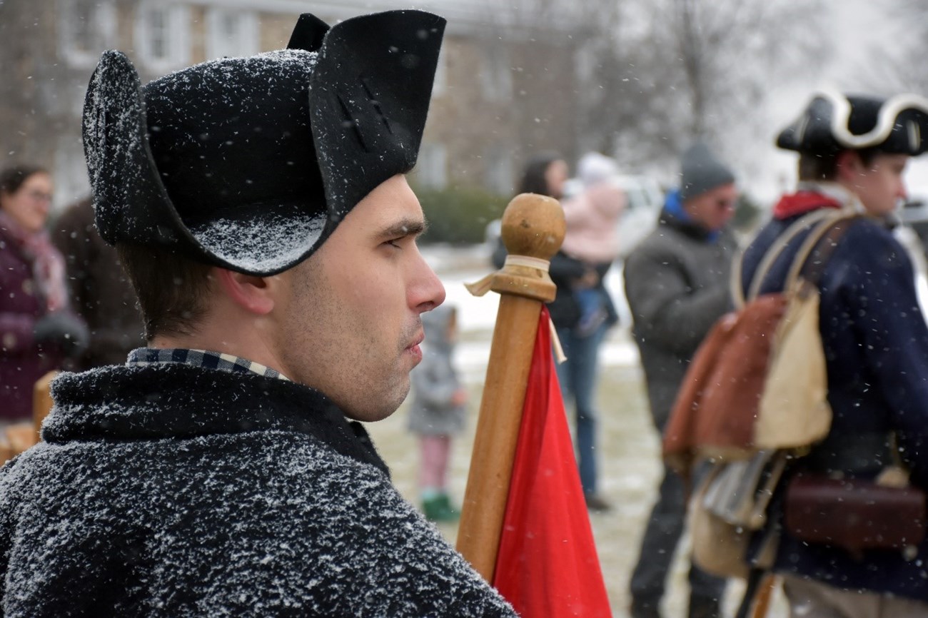 A person in historic garb stands among a crowd.