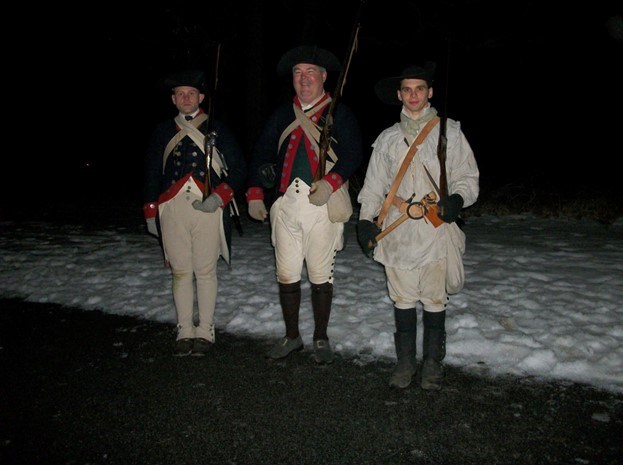 three people stand in historic revolutionary war uniforms