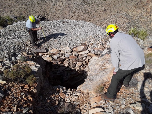An open mine shaft half covered by wooden boards
