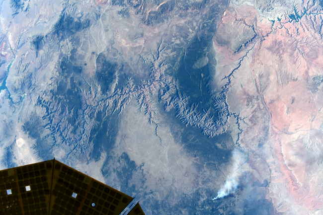 Grand Canyon National Park as seen from the International Space Station. Grand Canyon from space. A green and brown landscape with a long jagged canyon cut into the Earth.