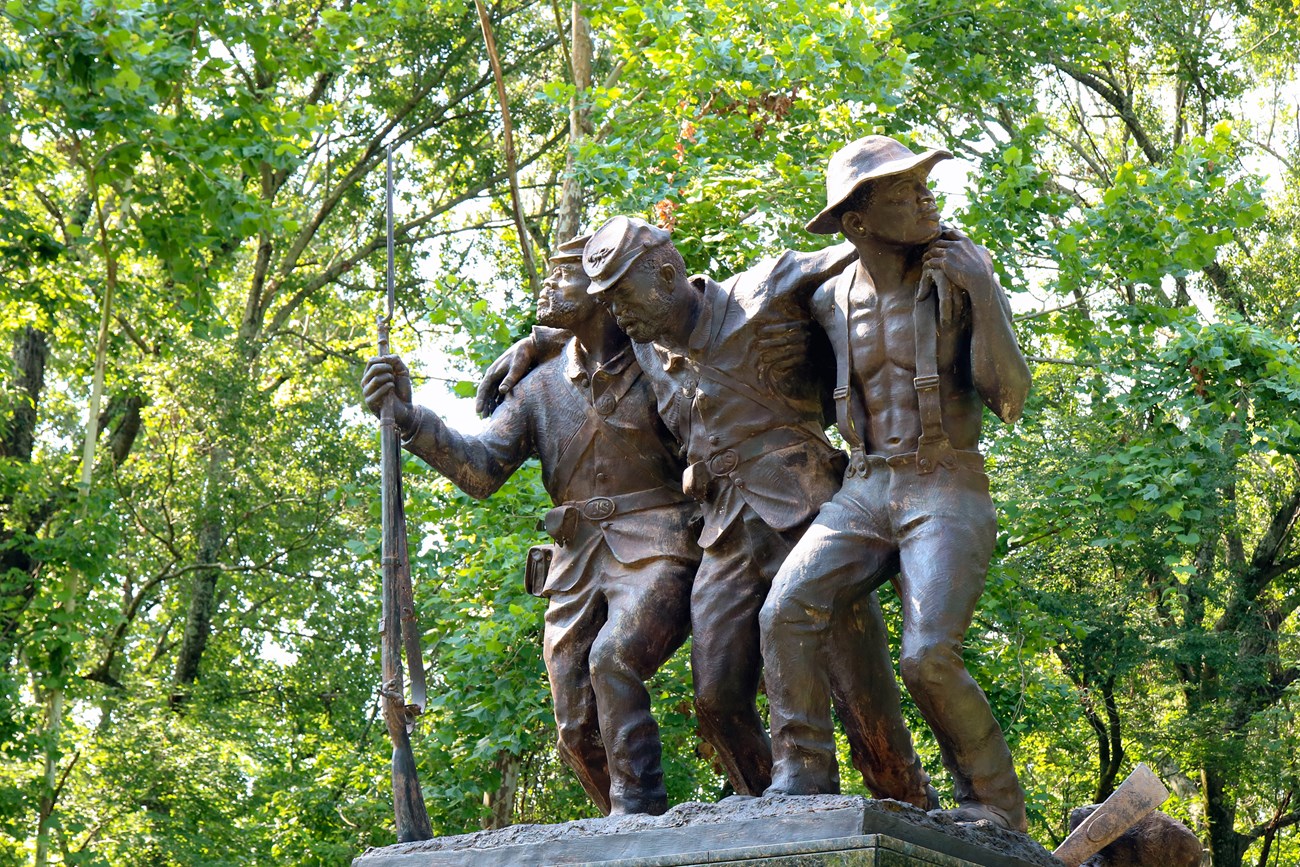 The Mississippi African American Monument honors the 1st and 3rd Mississippi Infantry Regiments, African Descent, and all Mississippians of African descent who participated in the Vicksburg Campaign. Three bronze statues of African American men standing hold each other up.