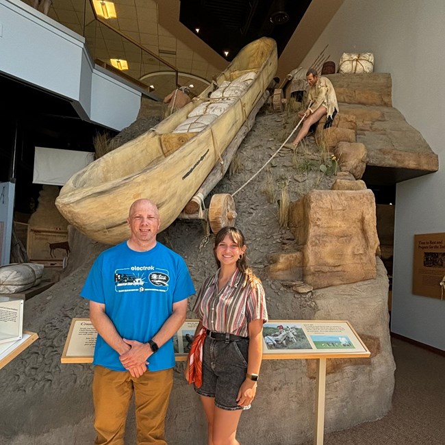 A woman and man standing in front of a canoe display