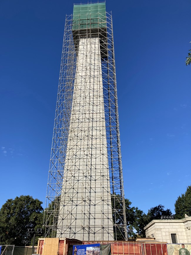The Bunker Hill Monument surrounded by scaffolding with the top portion covered in green mesh.