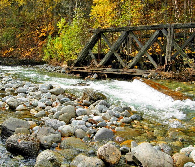 Moose Creek flows near a wooden structure and a rock stream bank during the fall.