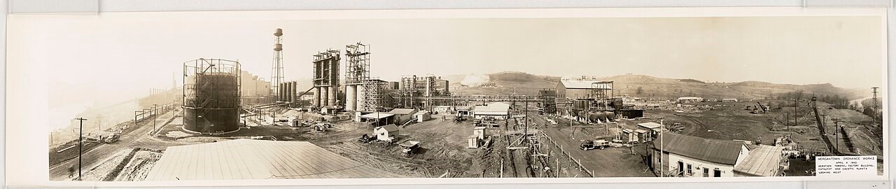 A black and white panoramic photo showing the construction of an industrial site.
