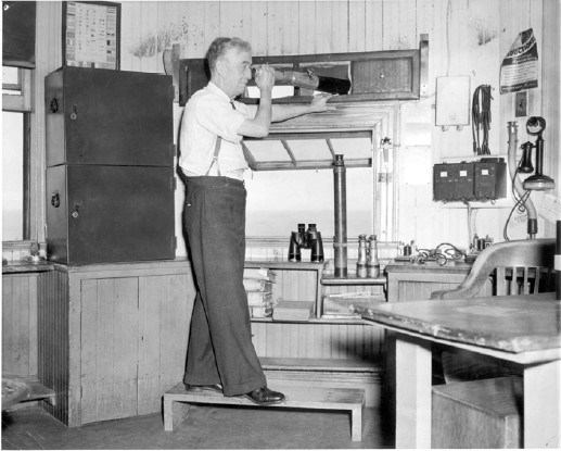 an older man stands on a bench, using a telescope to look out of a window