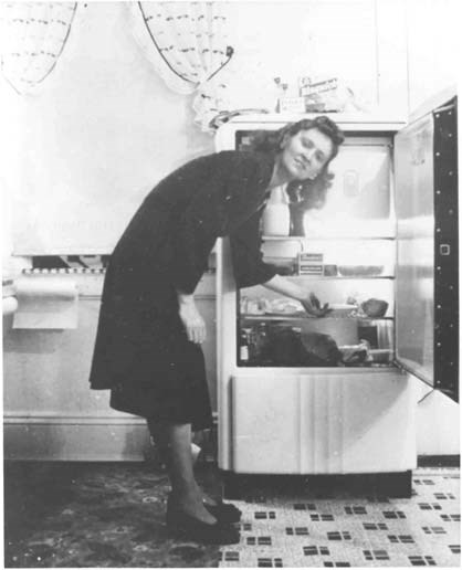 a woman stands in front of a refrigerator