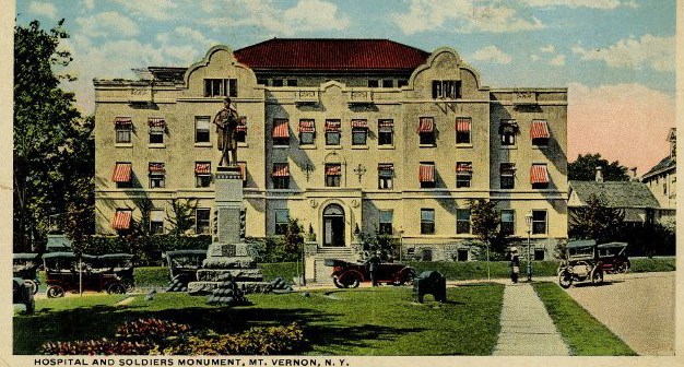 Tall statue of Soldier, set on green grass lawn, in front of large white building