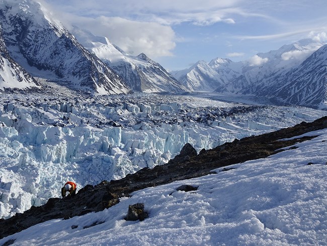 A scientist takes measurements on a glacier.