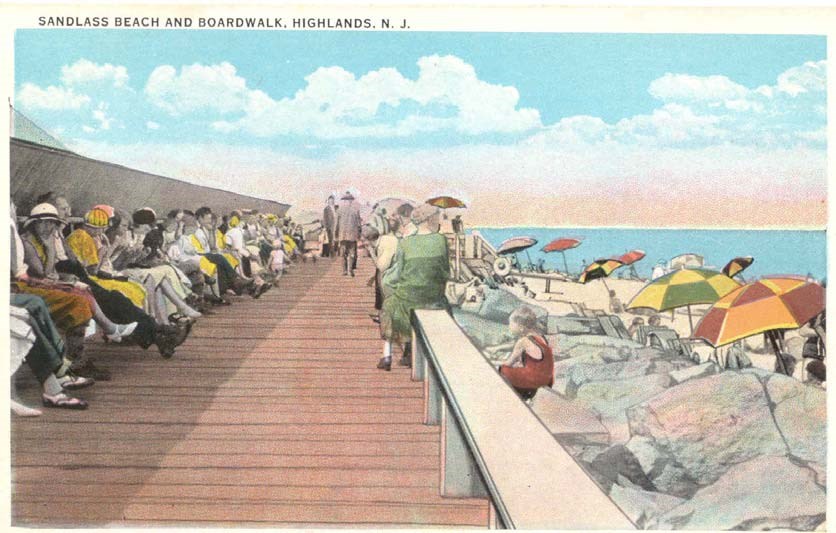 visitors sit along the boardwalk with bright umbrellas on the beach