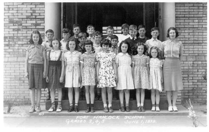 a group of young children stand on schoolhouse steps