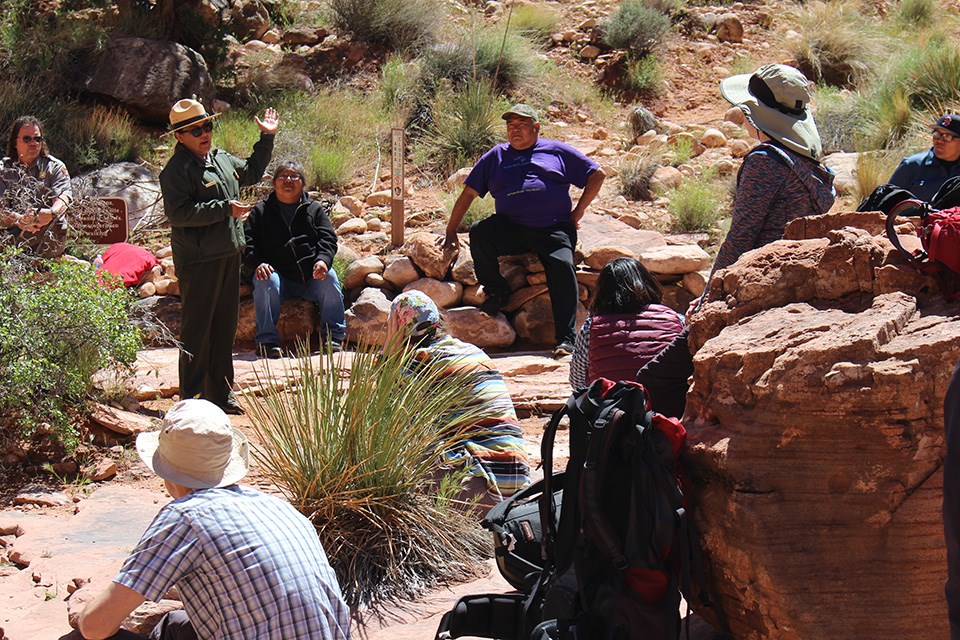 Rainbow Bridge Native American Consultation Committee, 2019 Park Ranger and a group of people talk outside in sandstone landscape